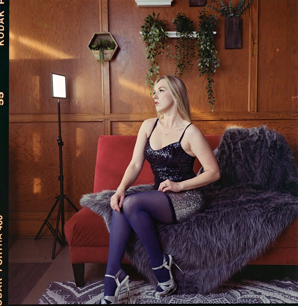 Blonde woman seated in sunlight studio portrait on Kodak portra 160 film in medium format shot with rolleiflex.