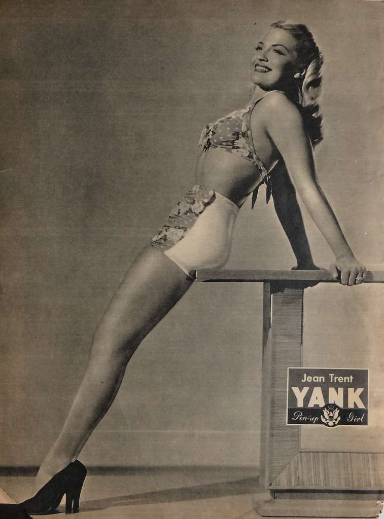 Pinup girl Jean trant poses in island swimsuit with long golden hair in black and white.